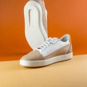 Beige with white shoe being showcased with an orange background